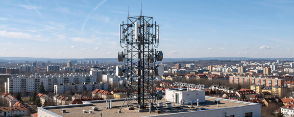 Telecommunication tower with antennas on a rooftop. 5G and 6G cellular network infrastructure in an urban city. Wireless mobile technology concept