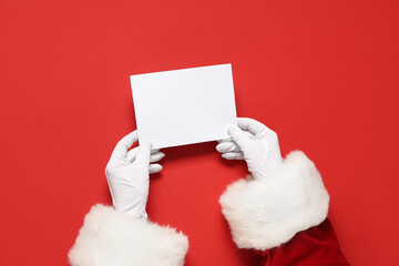 Santa Claus hands with blank card on red background, closeup