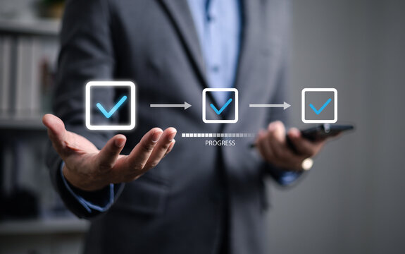 Businessman using check mark on checklist with progressive loading status to remind work in progress for project development management and idea tracking.