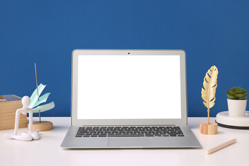 Fototapeta premium Modern laptop, decor and sticky notes on light table near color wall