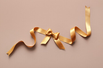 Bow made of beautiful golden ribbon on color background