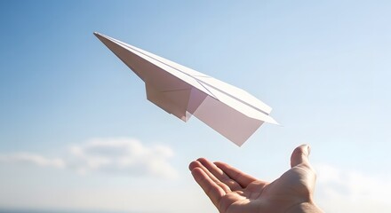Hand releasing a white paper airplane into a clear blue sky with clouds