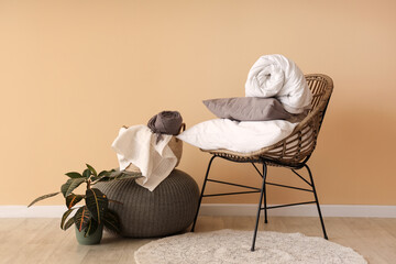 Armchair with pouf, pillows and blanket near beige wall in living room