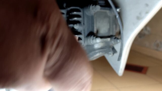 Close-up footage of a mechanic hand cleaning a dirty motorcycle spark plug using a cloth. Concept of engine maintenance, repair service, and vehicle care in workshop.