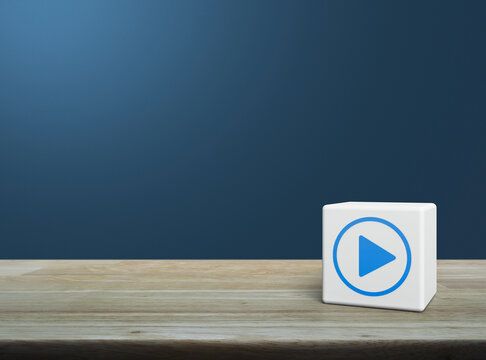 Play button flat icon on white block cube on wooden table over light blue wall, Business music online concept