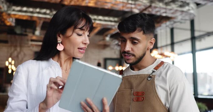 Conversation, manager or server with tablet in restaurant, instructions or teaching for booking app. Mentoring, staff support or people talking with digital menu, payment process or ordering tech