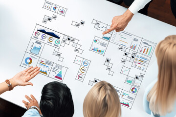A diverse group of professionals collaborates over a table filled with detailed charts and visual data, focusing on strategic planning and analysis for business success. Trope