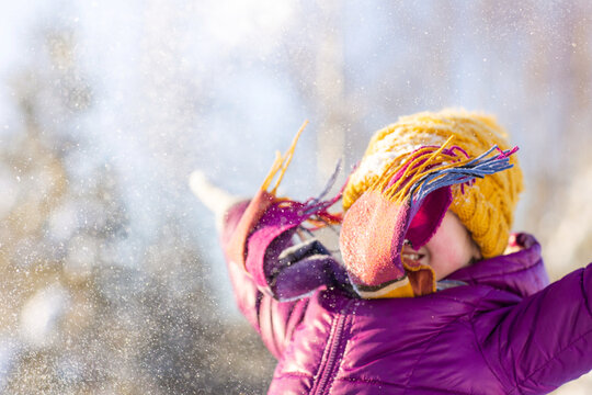 happy child playing with snow at resort in winter against background of forest outdoor. Games and activities for Christmas holidays in winter