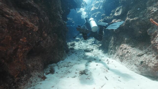 Scuba Diver Swimming Through a Narrow Coral Passage &mdash; Dramatic Underwater Exploration in a Scenic Tropical Reef Environment &mdash; Captured in Stunning 4K 60 FPS for Premium Stock Footage