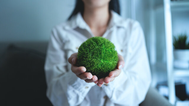 A woman is holding a green ball in her hand