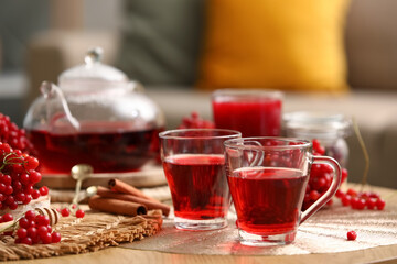 Cups of tasty viburnum tea on table in living room, closeup