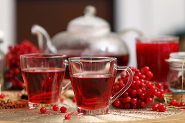 Cups of tasty viburnum tea on table in living room, closeup