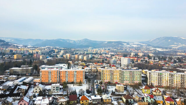 Aerial view of a city in a valley surrounded by snowy mountains with colorful apartment buildings in the foreground during winter