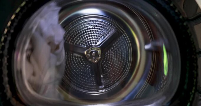 Close up inside view of modern tumble dryer drum spinning with motion blur. Abstract texture of clothes dryer machine working with laundry during cycle. Concept of Technology, Smart Home. 4k VDO