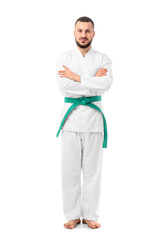 Young man with green belt practicing karate on white background
