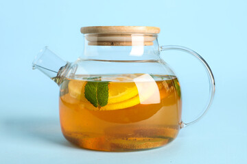 Teapot with tasty fruit tea on blue background, closeup