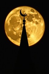 Silhouette of a mosque minaret with crescent moon against a full moon