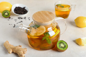 Teapot with tasty fruit tea on white grunge background, closeup