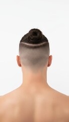 Rear view of a modern man's stylish hairstyle, showcasing a neat man bun with a sharp undercut fade against a clean white background