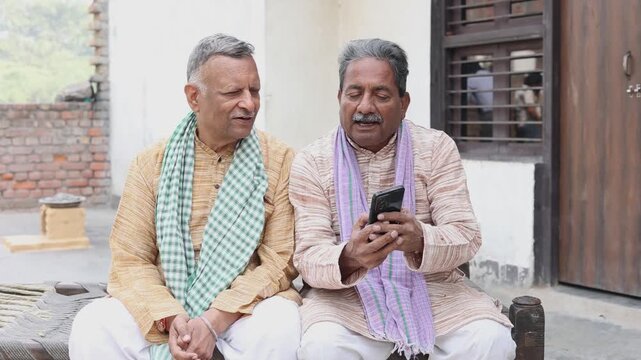 Senior rural indian men farmer using smart phone showing government scheme. Digital india concept. Fast 5G internet. Village people using wireless technology.
