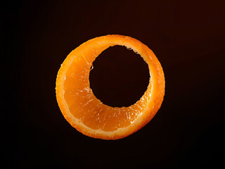 A bright orange peel spirals gracefully in dynamic, curved motion, appearing isolated and floating on dark background