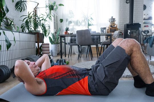 A man does abs exercises at home on a fitness carpet