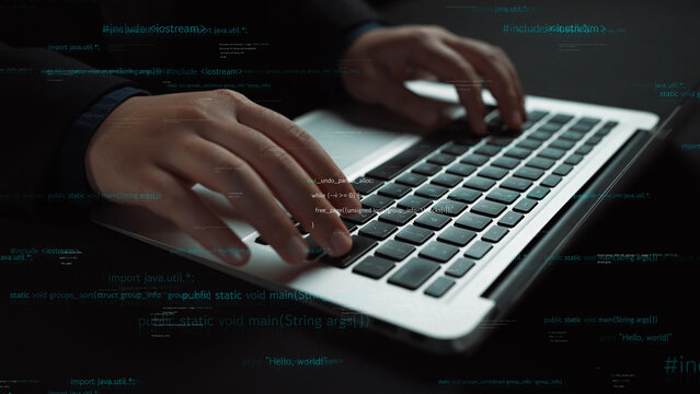 Close-up of hands engaged in typing on a modern laptop keyboard set in a dimly lit environment, featuring overlay graphics of code and digital symbols, symbolizing technology and innovation. Xenic
