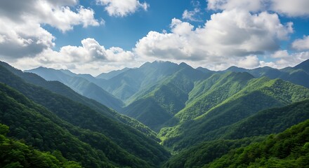 Lush, verdant mountain range under a bright blue sky dotted with puffy, white clouds, with deep valleys