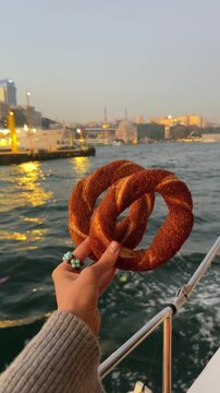 A Turkish simit in a person's hand.
A sesame seed bun against the backdrop of Istanbul.
A round flour bagel.
A fresh simit against the backdrop of the Bosphorus in the evening.