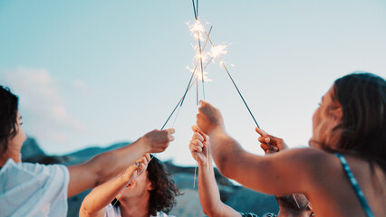 People, hands and sparkler with blue sky for new year, outdoor event or social gathering. Group, friends or fireworks with stick in celebration for holiday, weekend or bonding together in nature