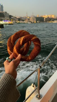 A Turkish simit in a person's hand.
A sesame seed bun against the backdrop of Istanbul.
A round flour bagel.
A fresh simit against the backdrop of the Bosphorus in the evening.