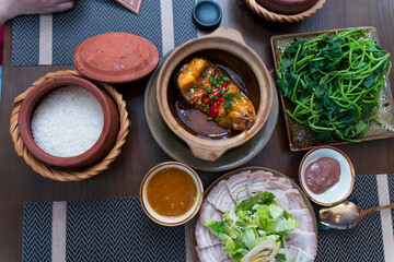 Traditional Hue lunch spread featuring clay pot rice, caramelized braised fish, boiled pork belly, and fresh sweet potato greens.