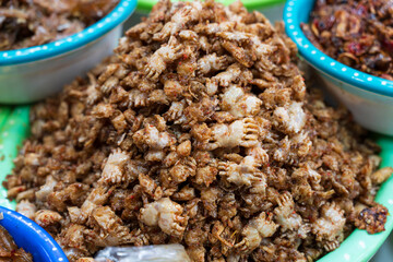 Large mound of seasoned, crispy baby crabs, a savory traditional delicacy displayed in a market basin in Hue, Vietnam.