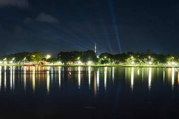 Dramatic green spotlights fan out over the Perfume River at night, illuminating boats and reflecting on the dark water surface.
