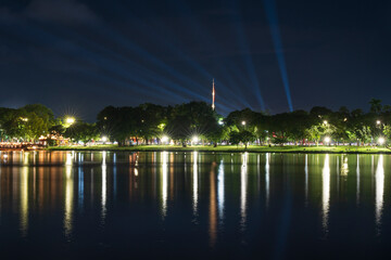 Dramatic green spotlights fan out over the Perfume River at night, illuminating boats and reflecting on the dark water surface.