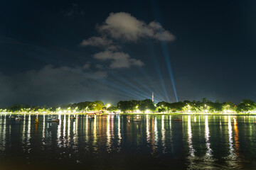 Dramatic green spotlights fan out over the Perfume River at night, illuminating boats and reflecting on the dark water surface.
