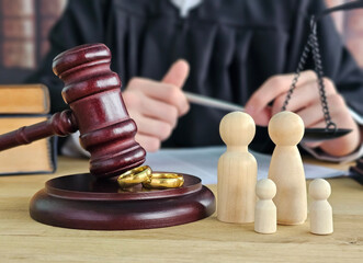 A gavel, small wooden figurines of parents and children, and a judge on a courtroom table with...