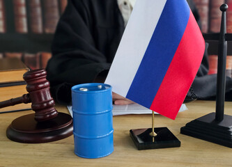 Legal proceedings involving Russian flag and oil barrel in a courtroom setting while a judge...