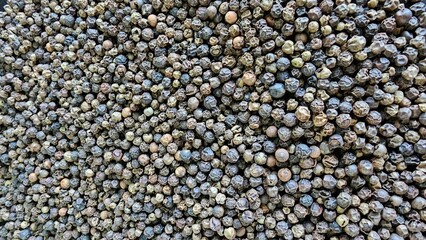 Large pile of black peppercorns showcasing the rich texture and colors in a spice preparation area concept