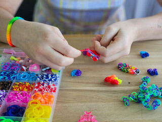 Crafting colorful rubber band bracelets on a wooden table