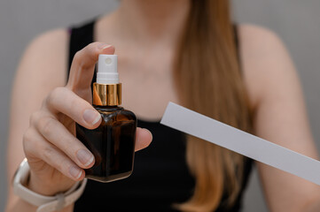 Fototapeta premium A woman sprays fragrant perfume onto a blotter test strip and smells the fragrance composition.