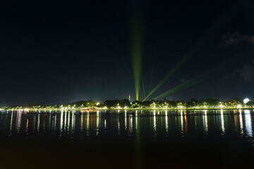 Dramatic green spotlights fan out over the Perfume River at night, illuminating boats and reflecting on the dark water surface.