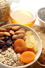Making granola. Oat flakes, dried fruits and other ingredients on white table, closeup