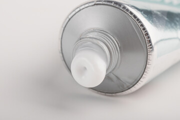 Close-up of cosmetic tube opening on light background. Minimal skincare packaging detail with clean modern aesthetic.