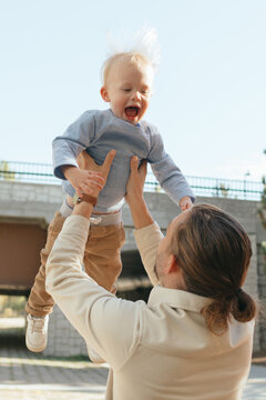 Father lifting toddler son creating playful moment