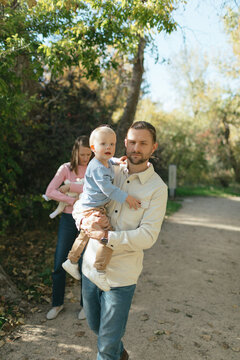 Father holding son with family walking outdoors in park