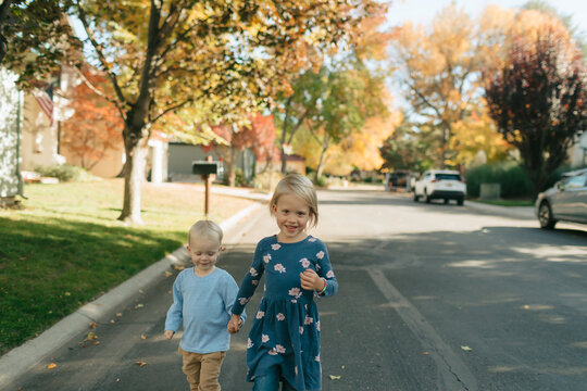 Siblings walking hand in hand on autumn street