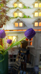 Purple tulips in vase with traditional nutcracker and wooden dollhouse