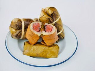 Steamed sticky rice with banana placed on a plate on white background. A delicious Thai dessert. 