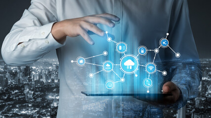 A business professional interacts with a tablet displaying futuristic digital networks and cloud technology, set against a nighttime city skyline, symbolizing innovation. Tessel